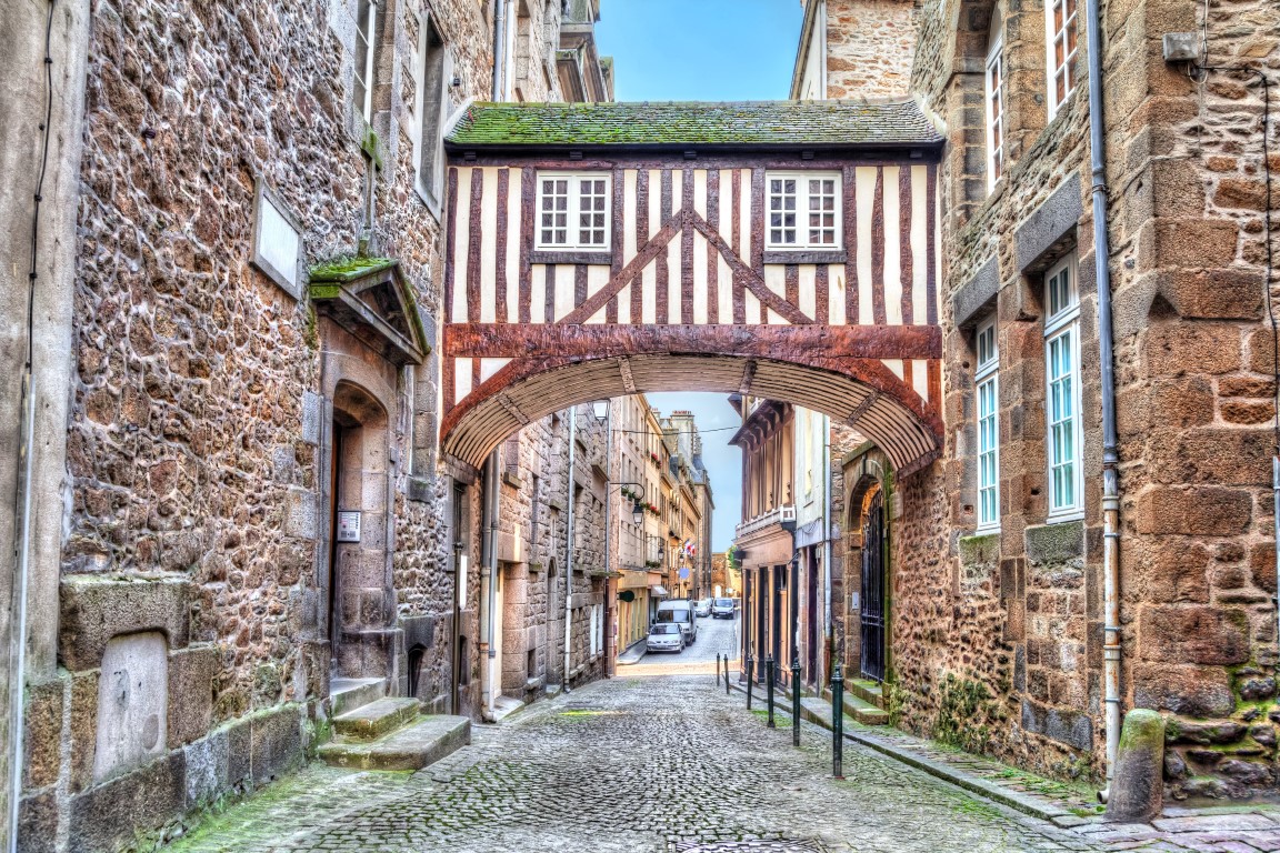 Hölzerne Brücke zwischen zwei Gebäuden in einer engen Straße in Saint-Malo, Bretagne, Frankreich