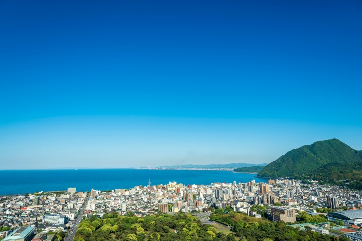 Stadtansicht von Beppu Stadt und Beppu Bucht mit blauem Himmel Hintergrund, Oita, Kyushu, Japan