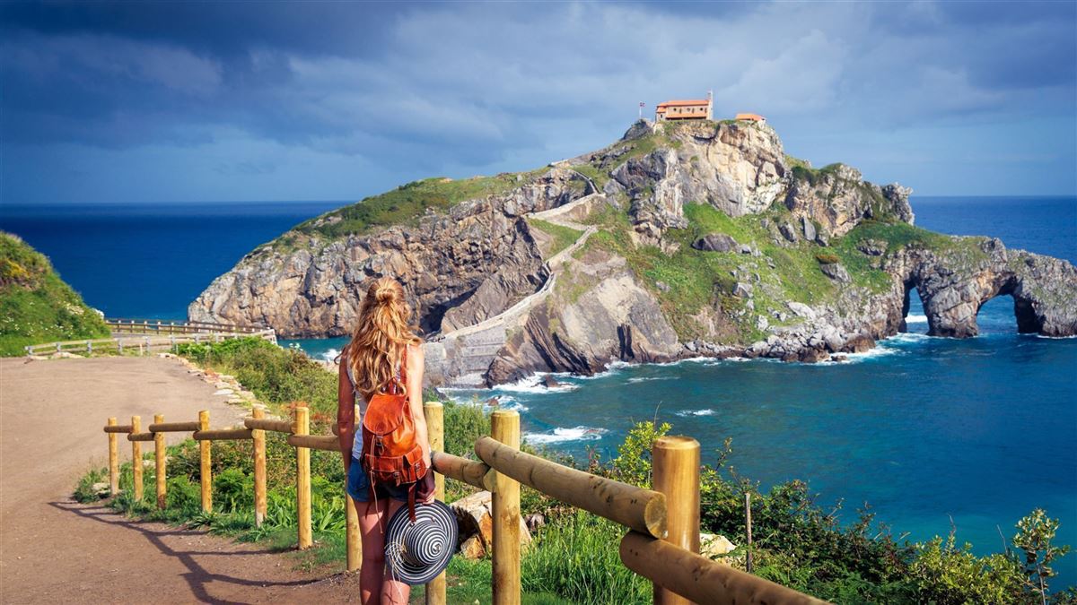 Touristin betrachtet die Aussicht auf San Juan de Gaztelugatx in der Nähe von Bilbao – Baskenland