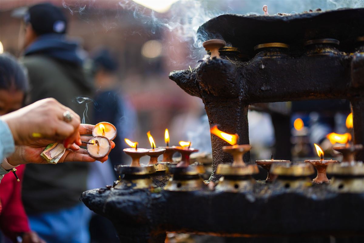 Brennende Butterlampen vor dunklem Metallaltar am Durbar Square in Nepal